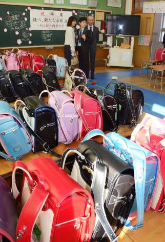 寄付するランドセルと卒業生ら＝鹿児島市の西紫原小学校