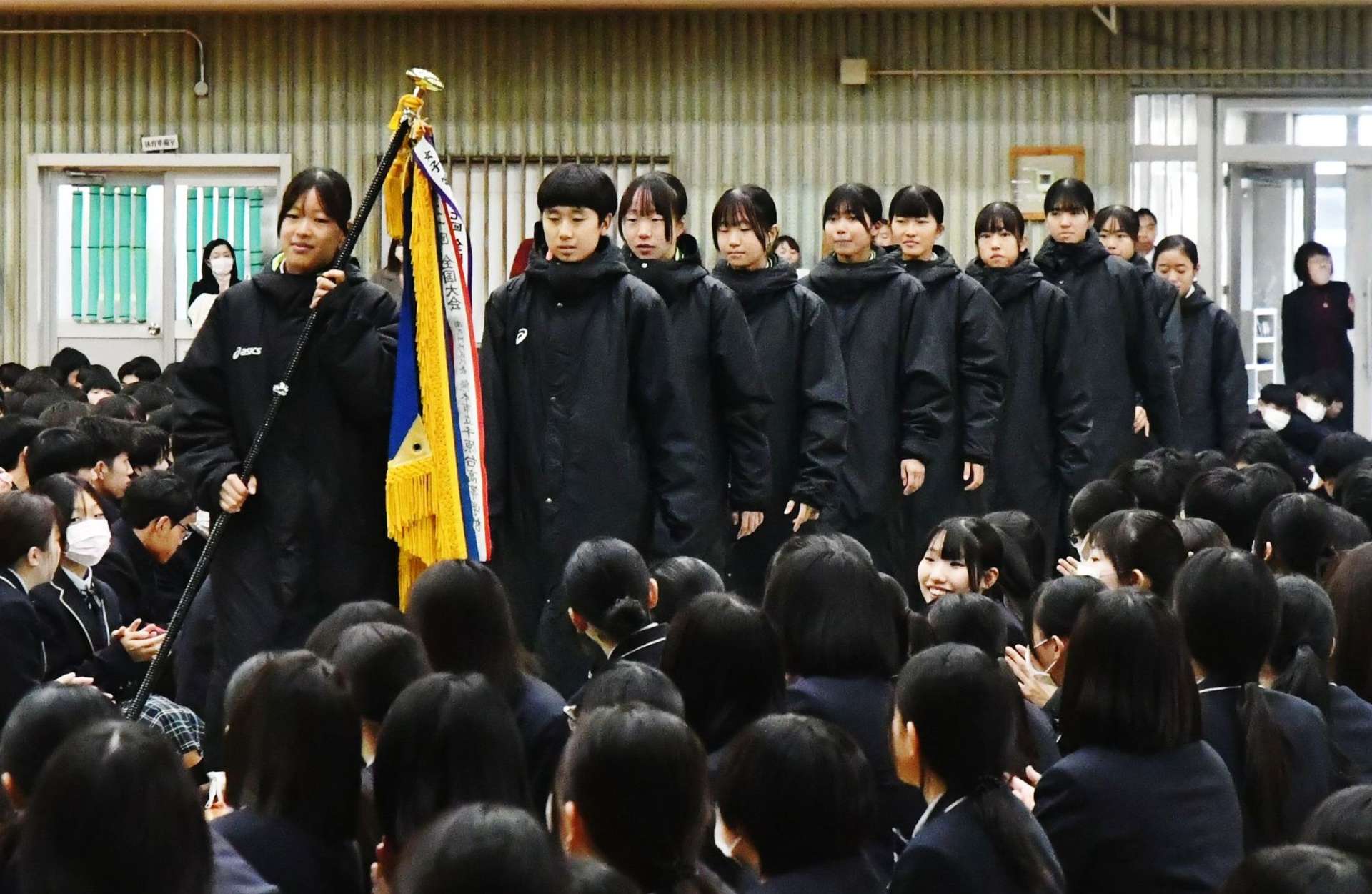 全校生徒に拍手で迎えられる駅伝部女子の選手＝鹿児島市の鹿児島高