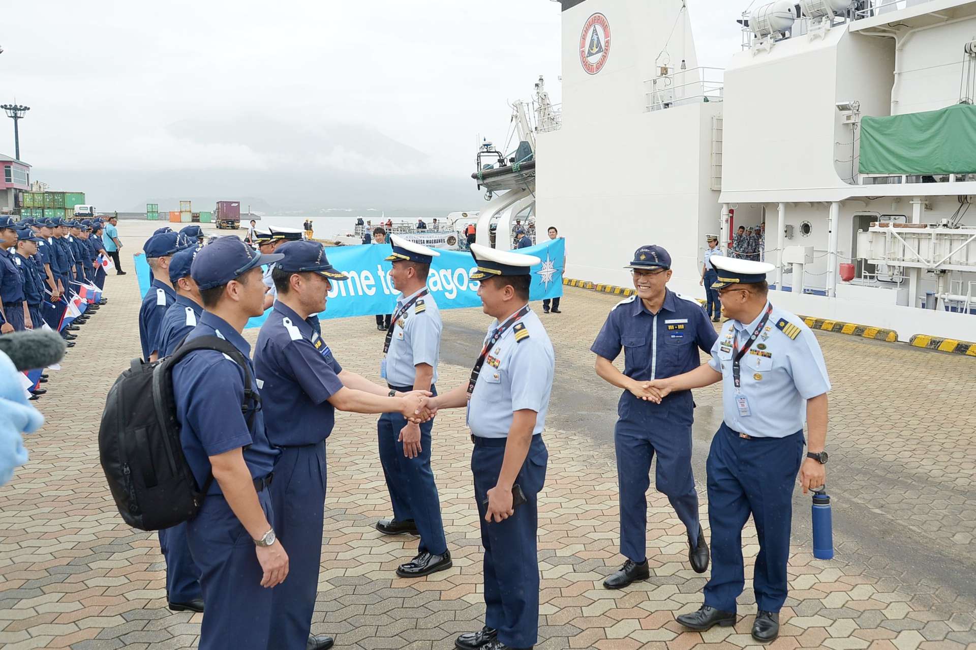 フィリピン巡視船乗組員（右側）と握手を交わす第１０管区海上保安本部の職員＝鹿児島市の鹿児島港本港区北ふ頭