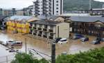 茶色く濁った水に浸水する車や建物＝８月８日午前７時３５分ごろ、霧島市向花町