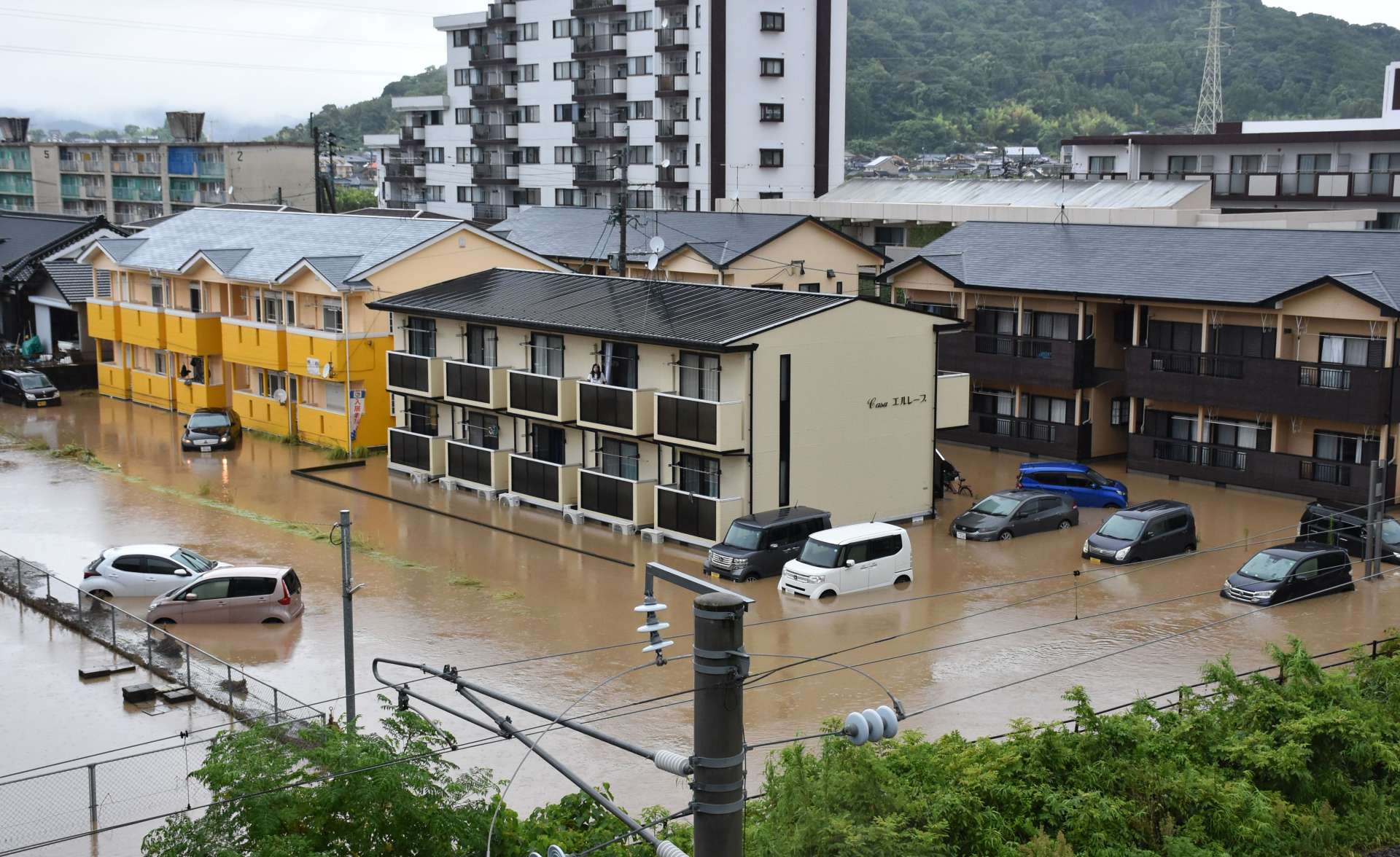 茶色く濁った水に浸水する車や建物＝８月８日午前７時３５分ごろ、霧島市向花町