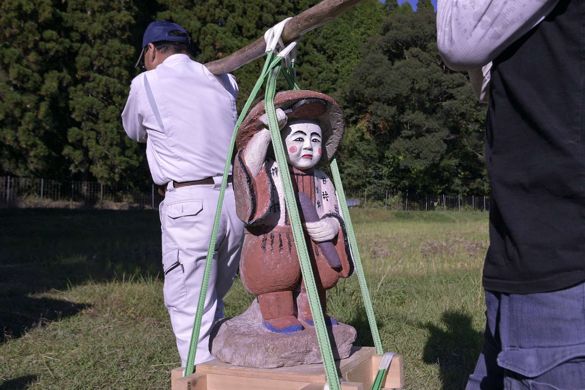 下狩宿集落の住民に担がれ田んぼを回る田の神＝１４日、さつま町求名
