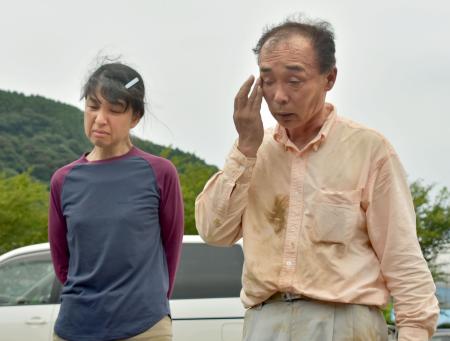 　知人らに大和晃さんが乗っていた車とみられる車体の一部を見つけたと報告する父卓也さんと母忍さん＝２４日午後、熊本県大津町
