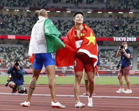 　男子１００メートル決勝　優勝したイタリアのラモントマルチェル・ヤコブス（左）と健闘をたたえ合う中国の蘇炳添＝国立競技場