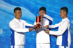 　北京冬季五輪の聖火到着式典で、聖火をランタンからトーチに移す参加者＝２０日、北京（ロイター＝共同）