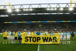 　ドルトムントとディナモ・キーウの平和を求める親善試合を前に「ＳＴＯＰ　ＷＡＲ（戦争をやめろ）」の横断幕を掲げる選手ら＝２０２２年４月、ドイツ・ドルトムント（ロイター＝共同）