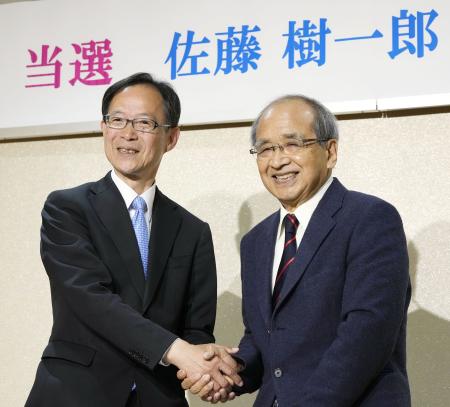 　現職の広瀬勝貞知事（右）と握手する佐藤樹一郎氏＝９日夜、大分市