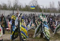 　３月３１日、ウクライナ・ブチャでロシア占領下に犠牲となった人々を追悼する式典が開かれ、戦死したウクライナ兵の墓に花を供える親族（ＡＰ＝共同）