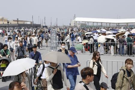 　大阪メトロ夢洲駅（右奥）を利用して万博会場に向かう人たち＝４月、大阪市此花区の夢洲