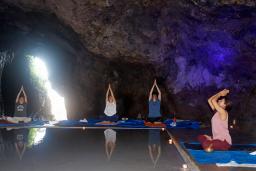 　パワースポット「青の洞窟」で村上デビさん（右端）の指導のもと、ヨガを行う人たち＝１７日午後、石川県珠洲市