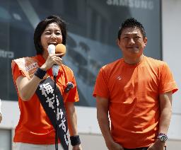 　比例代表で当選を決めた梅村みずほ氏（左）に花束を渡した参政党の神谷代表＝２０日午後８時２５分、東京都新宿区