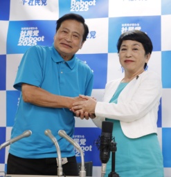 　比例代表で当選を決めたラサール石井氏（左）と握手する社民党の福島党首＝２１日午前４時１４分、東京都千代田区