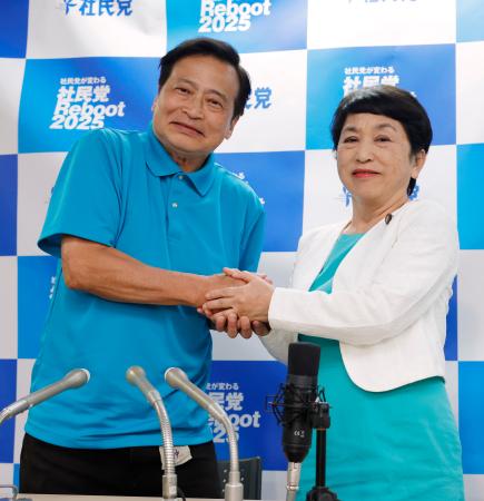 　比例代表で当選を決めたラサール石井氏（左）と握手する社民党の福島党首＝２１日午前４時１４分、東京都千代田区