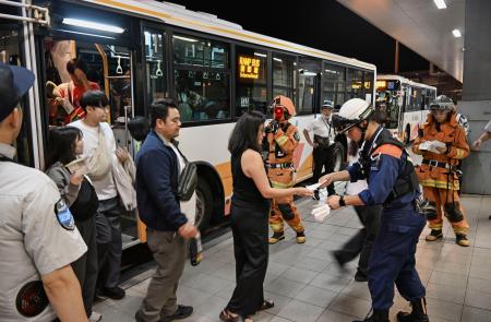 　関西空港に緊急着陸したユナイテッド航空機から避難し、バスで誘導される乗客＝１２日午後８時５８分