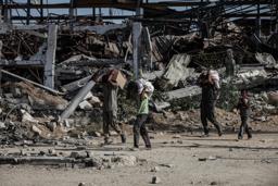 　２１日、イスラエル軍が攻勢をかけるガザ中部で、配給物資を運ぶ人たち（ゲッティ＝共同）