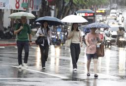 　台風１８号の影響で雨が降る中、歩く人たち＝２３日、台北（ＡＰ＝共同）
