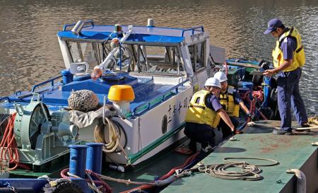 　事故を起こしたとみられる船を調べる海上保安庁の職員ら＝８日午前、東京都中央区