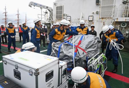 　巡視船の甲板に積み込んだ通信機材をベルトで固定する海上保安庁の隊員ら＝８日午後、富山県射水市