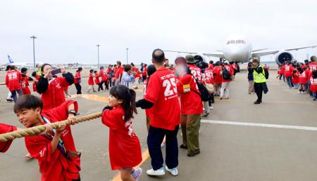 　イベントで、綱でジェット機を引っ張る人たち＝１３日午前、成田空港