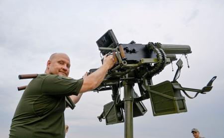 　機関銃を構えるビタリー・ズイエフさん＝７月、キーウ（共同）