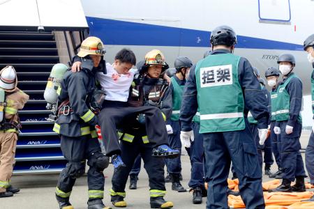 　旅客機事故を想定した訓練で、機内から救出された負傷者役＝１６日午後、成田空港
