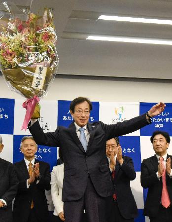 　神戸市長選で４選を果たし、花束を掲げる久元喜造氏＝２６日夜、神戸市中央区