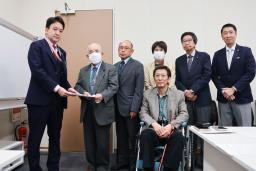 　警察庁の担当者に要請文を手渡す「犯罪被害補償を求める会」の藤本護代表理事（左から２人目）＝２９日午前、国会