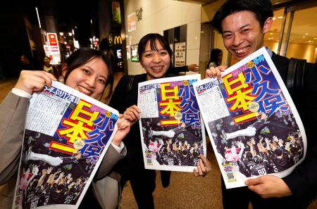 　ソフトバンクの日本一を伝える号外を手に笑顔の人たち＝３０日夜、福岡市