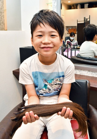 美容室で、カットした髪を持つ追立結吏君＝鹿児島市東谷山２丁目