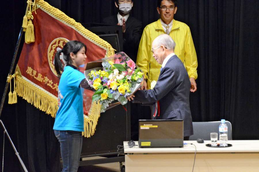 大龍小の創立記念式典の講演を終え、児童から花束を手渡される赤﨑勇さん＝2014年２月、鹿児島市のかごしま県民交流センター