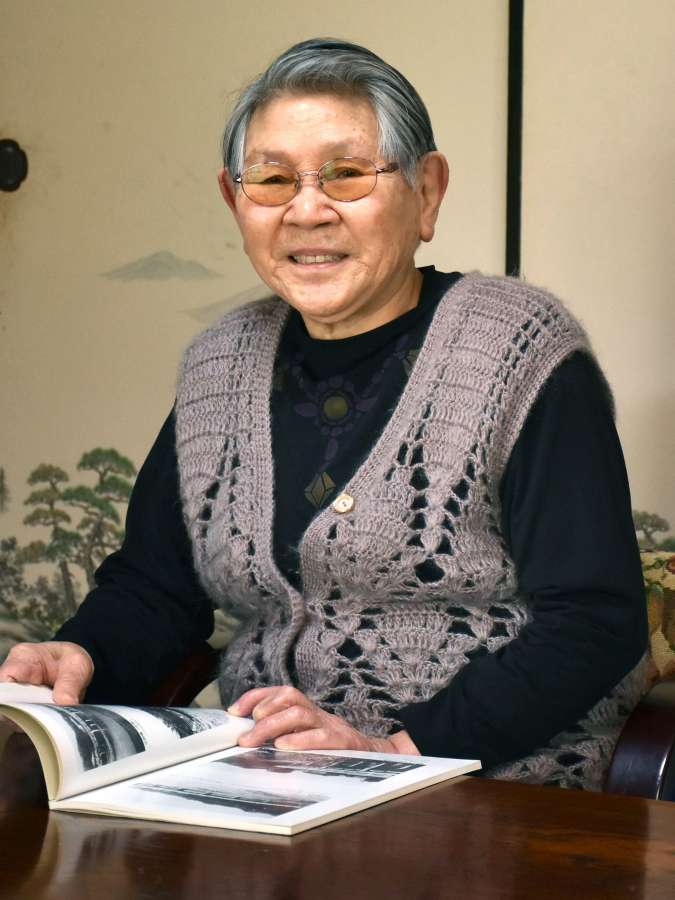 当時の写真を見ながら語る久保キク子さん＝姶良市蒲生