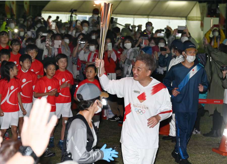 セレブレーション会場に入る聖火ランナーの恵俊彰さん＝２８日午後７時４５分、指宿市営陸上競技場