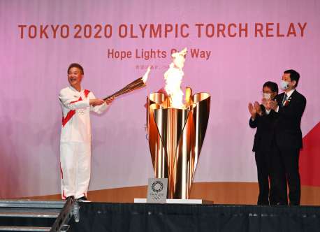 トーチの火を聖火皿に移す恵俊彰さん＝２８日午後７時４６分、指宿市営陸上競技場