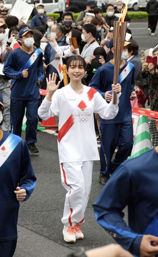 手を振り笑顔で走る聖火ランナーの上白石萌歌さん＝２８日、南九州市知覧町郡