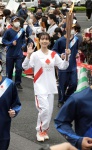 手を振り笑顔で走る聖火ランナーの上白石萌歌さん＝２８日、南九州市知覧町郡