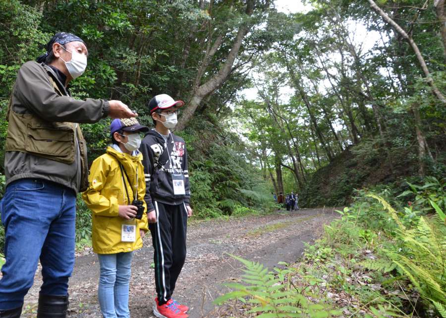 地元の子どもたちに奄美の自然の魅力を伝える奄美大島エコツアーガイド連絡協議会長の喜島浩介さん（左）＝３月、奄美大島の金作原国有林