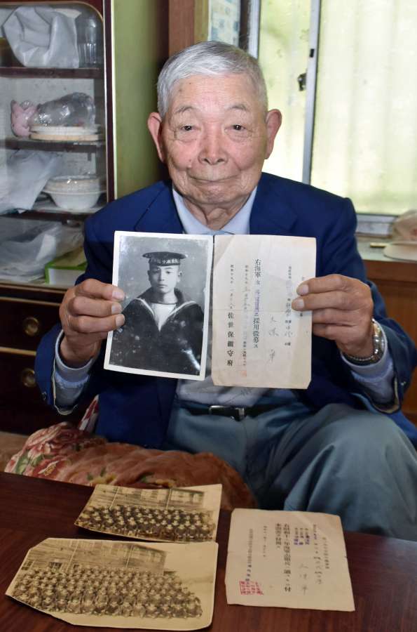 海軍兵時代の写真や資料を掲げ、不戦を訴える久保卓さん＝錦江町田代川原