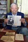 海軍兵時代の写真や資料を掲げ、不戦を訴える久保卓さん＝錦江町田代川原