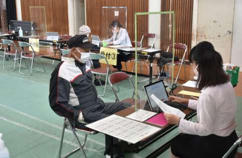 ワクチン接種のインターネット予約をしてもらう高齢者=18日、南大隅町根占川北の町体育館