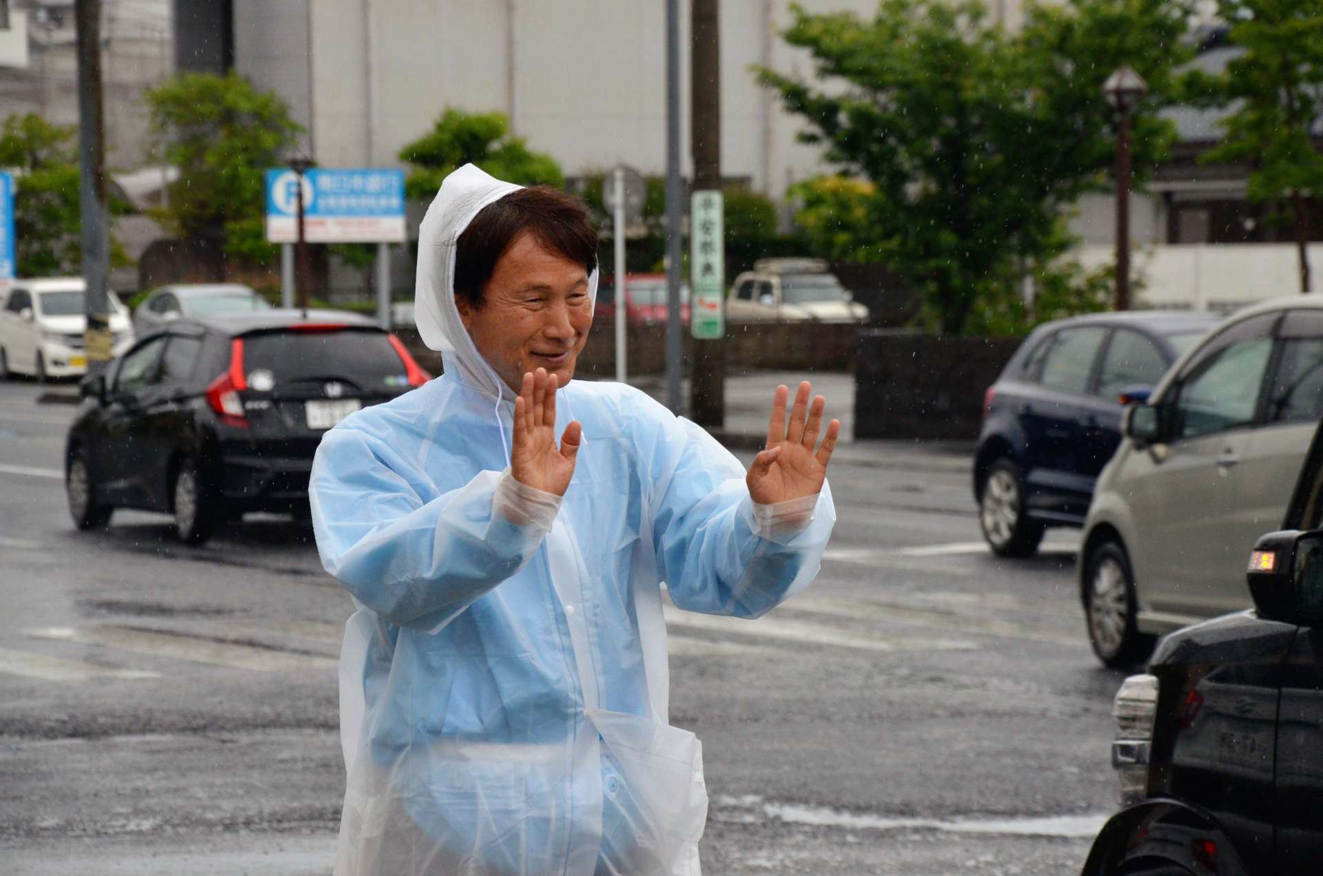 行き交う車に手を振る三反園訓氏
