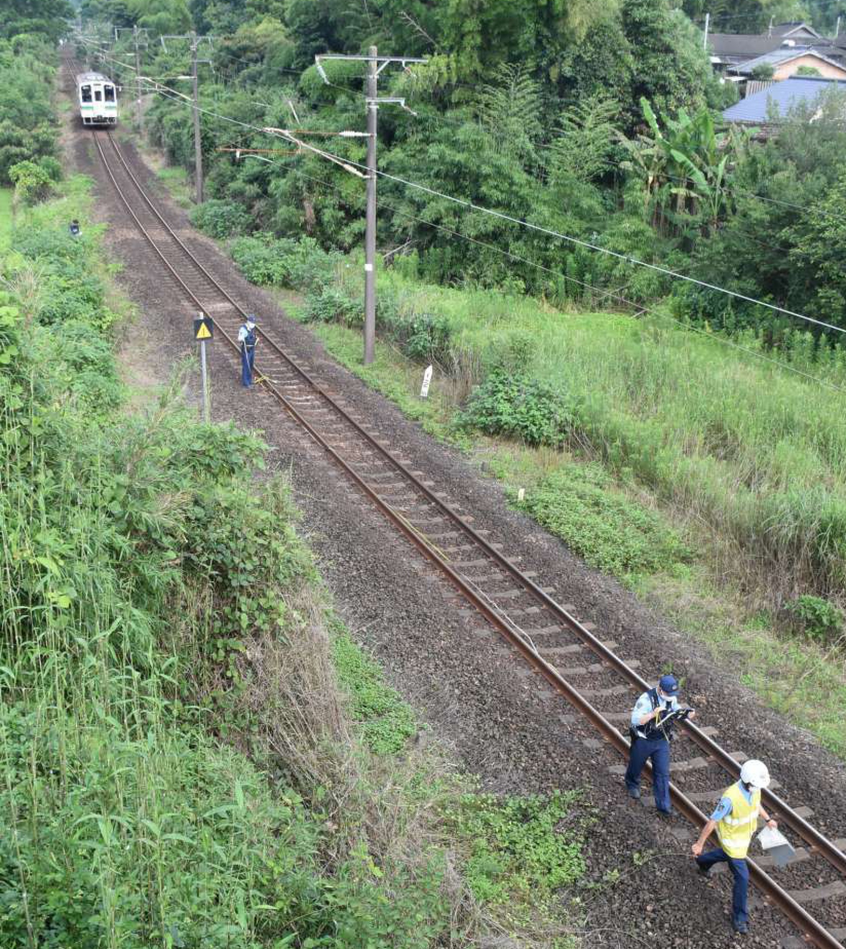 事故現場付近を調べる出水署員ら＝20日午後4時40分ごろ、出水市野田町下名