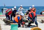 引き揚げられた九七艦攻のものとみられる部材を調べる関係者＝２３日午後、西之表市国上沖