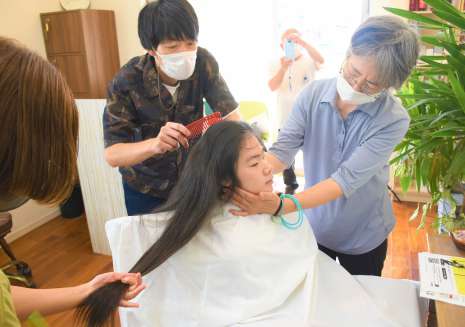 ロングヘアをカットしてもらう田中茜さん＝南さつま市加世田地頭所