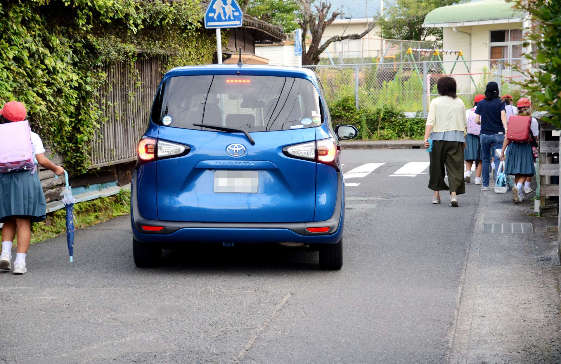 狭い生活道路を通行する児童ら＝霧島市国分清水１丁目（画像は一部加工してあります）