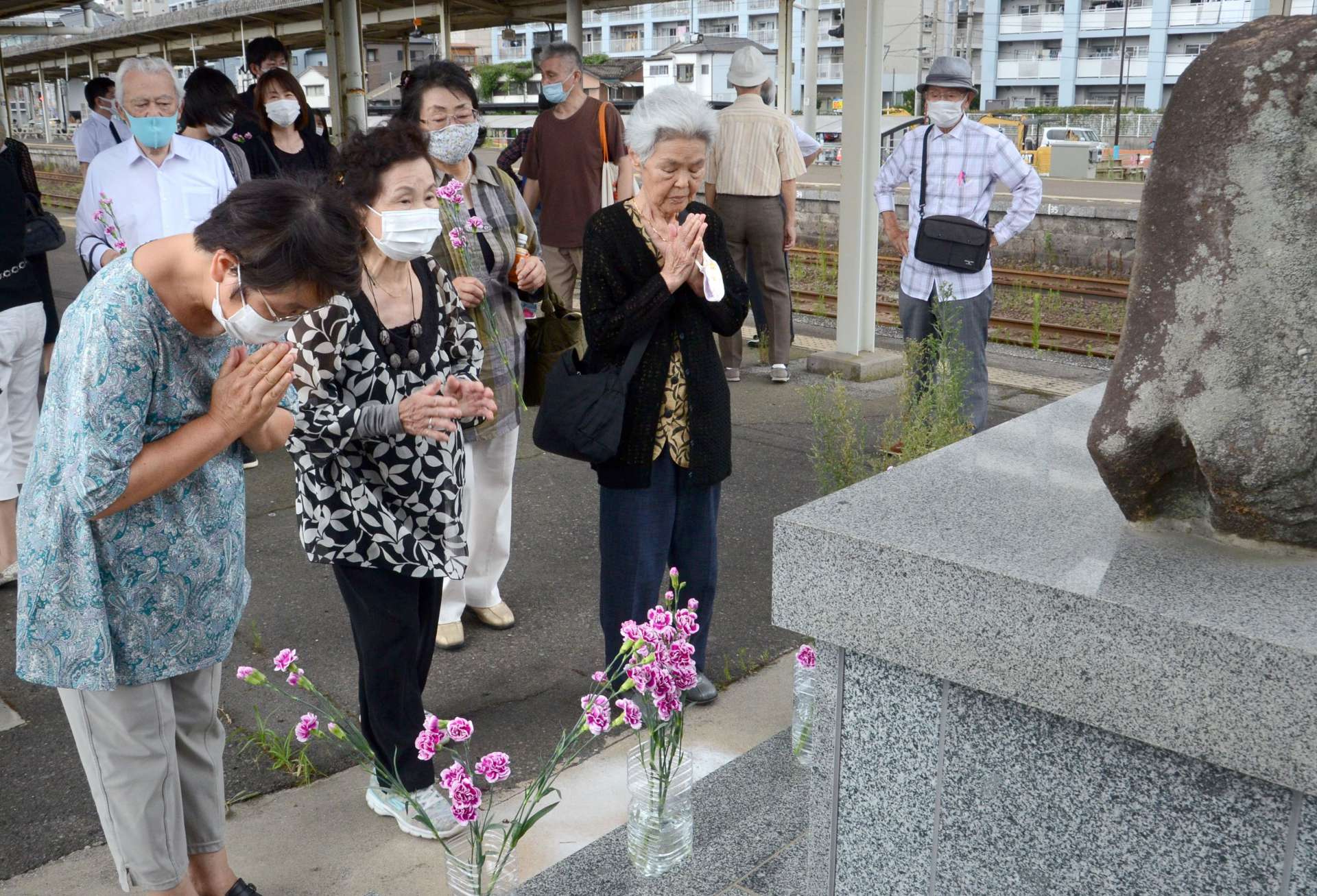駅に建つ慰霊碑にお参りする参加者ら＝鹿児島市のＪＲ鹿児島駅