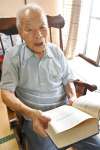戦没者名簿を載せた戦誌を持つ下津貫純義さん＝鹿児島市東坂元２丁目