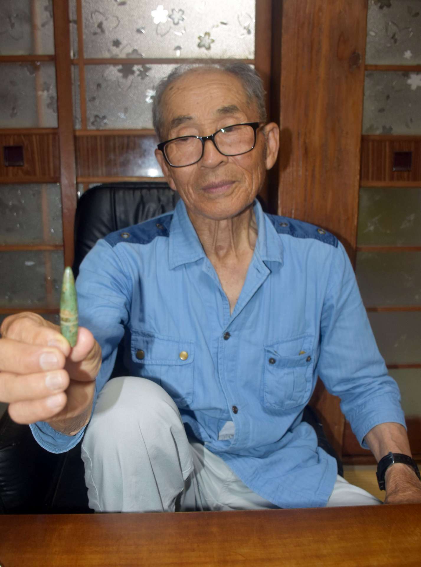 銃弾を手に、空襲の様子を振り返る徳田鉄美さん＝阿久根市折口