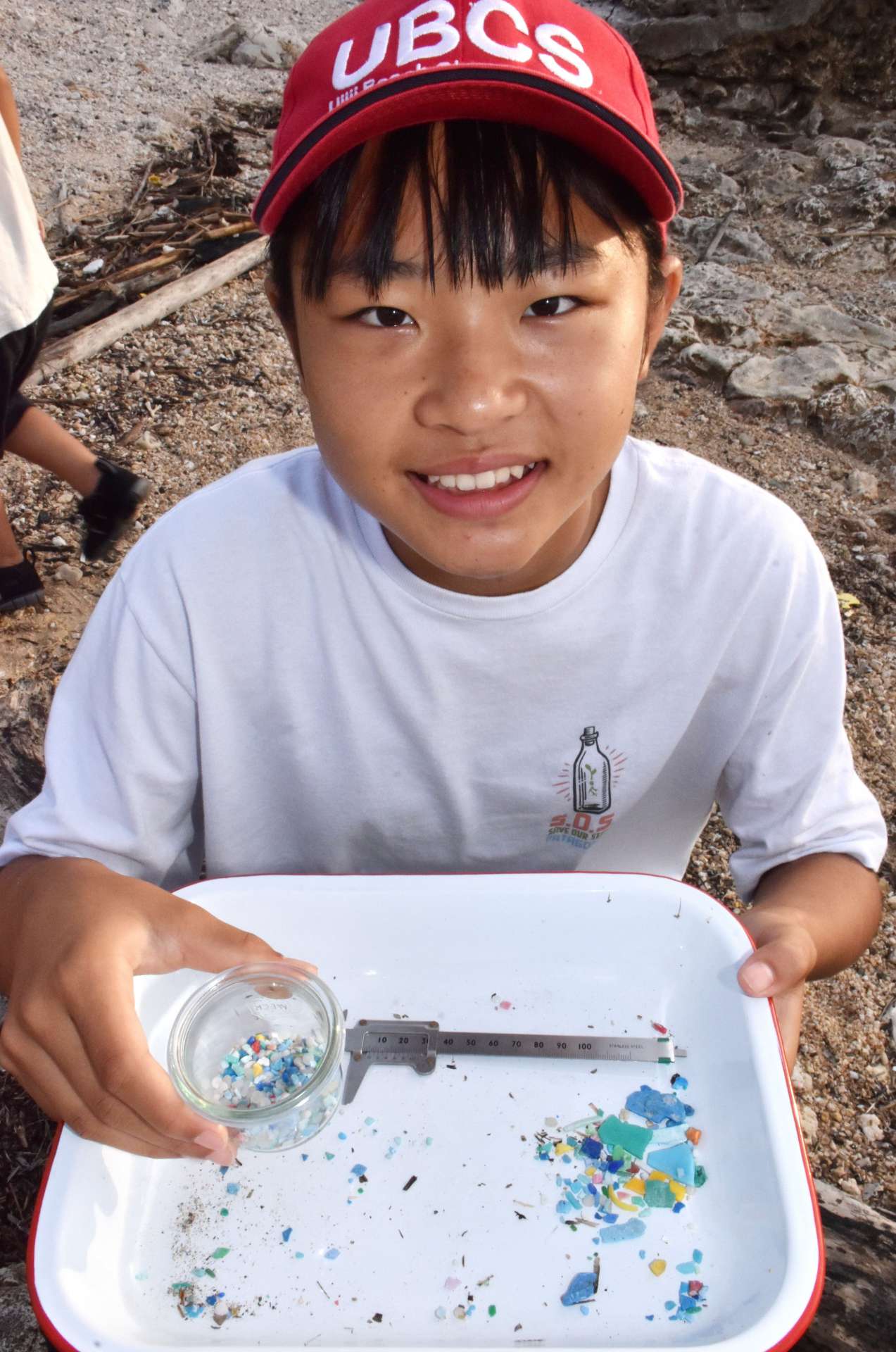 拾い集めたマイクロプラスチックの瓶詰めを手にする竿りりさん