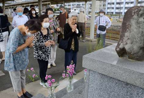 2021年7月、駅構内に建つ空襲犠牲者の慰霊碑にお参りする参加者ら＝鹿児島市のＪＲ鹿児島駅