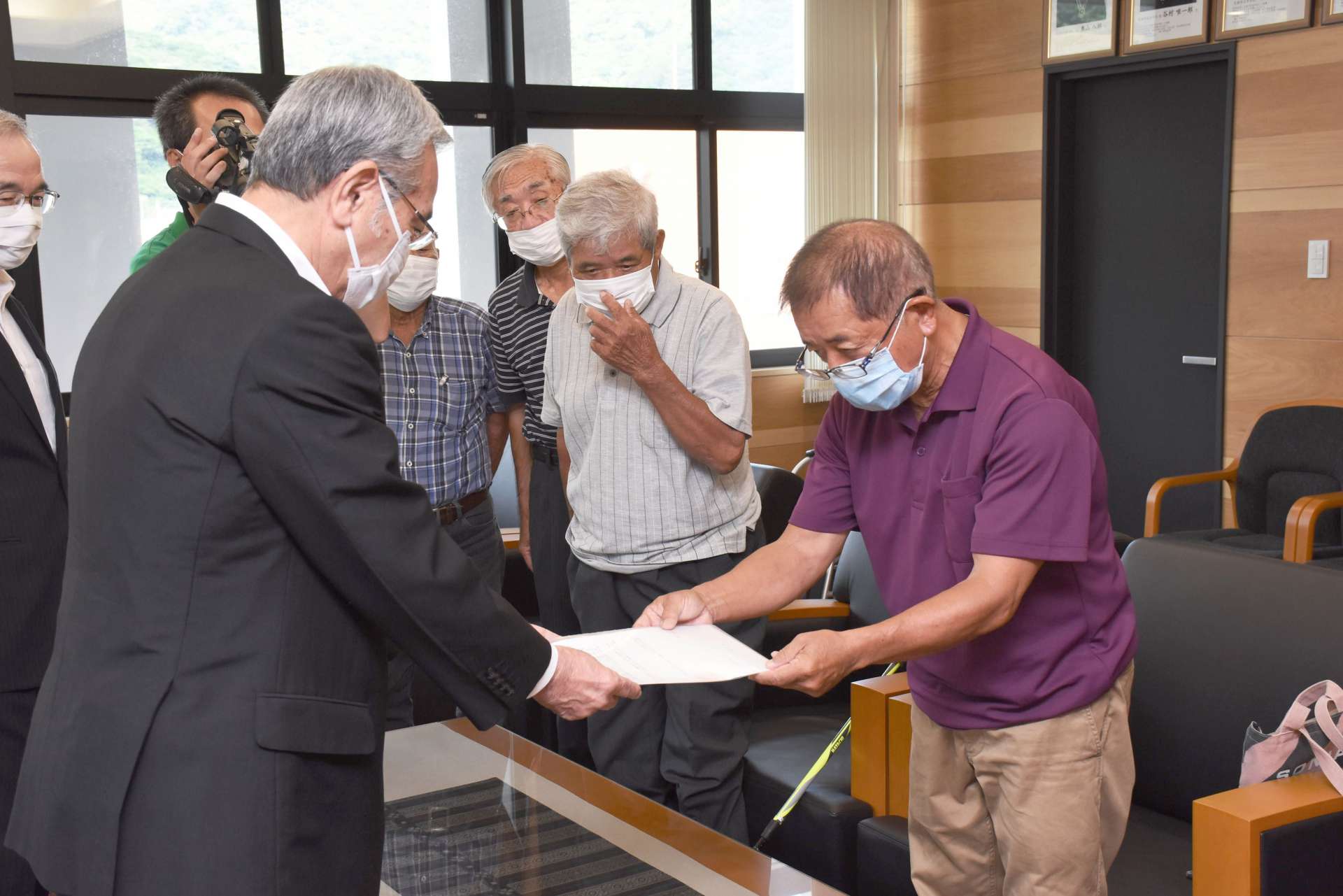 朝山毅市長（左）に滝名の公募中止を求める小湊集落の住民＝１７日、奄美市役所